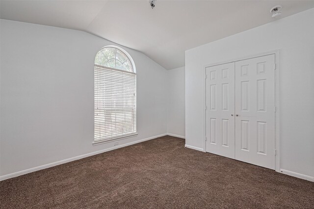 19826 Imperial Stone Dr, Houston, TX 77073 - unfurnished bedroom with vaulted ceiling, dark carpet, a closet, and baseboards