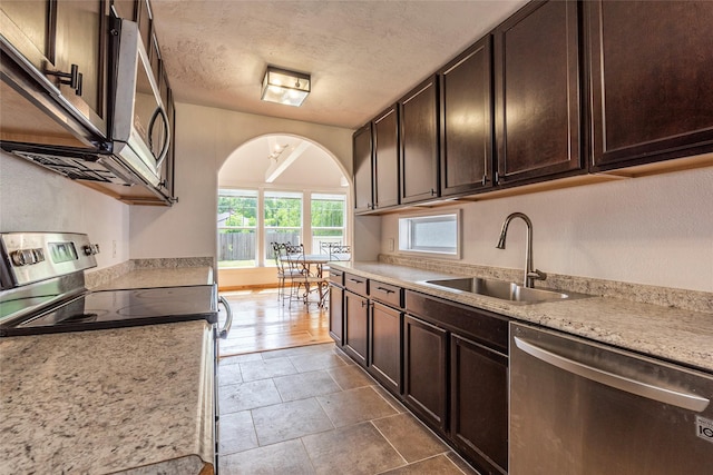 719 Shaver St, Pasadena, TX 77506 - kitchen featuring stainless steel appliances, dark brown cabinetry, arched walkways, and a textured ceiling