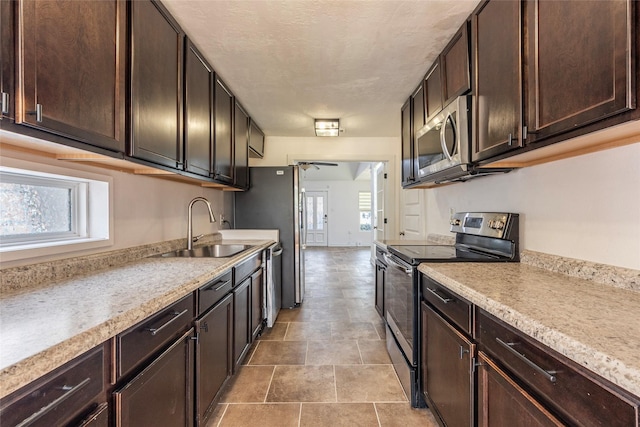719 Shaver St, Pasadena, TX 77506 - kitchen with appliances with stainless steel finishes, dark brown cabinets, light countertops, and stone finish floors