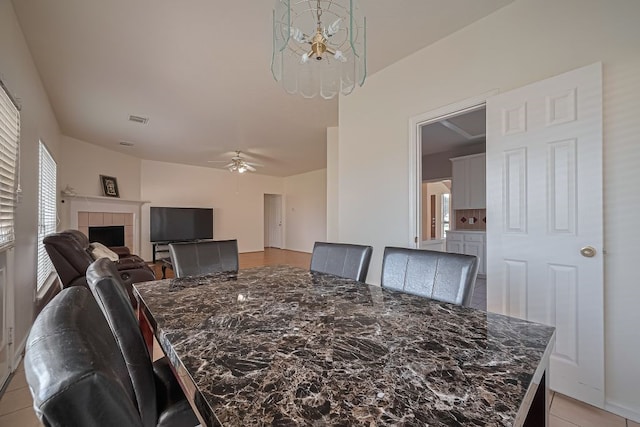 14723 Belterraza Dr, Houston, TX 77083 - dining room with a chandelier, a ceiling fan, a fireplace, and light tile patterned flooring