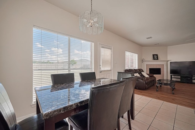 14723 Belterraza Dr, Houston, TX 77083 - dining area with a chandelier, light tile patterned floors, and a tile fireplace