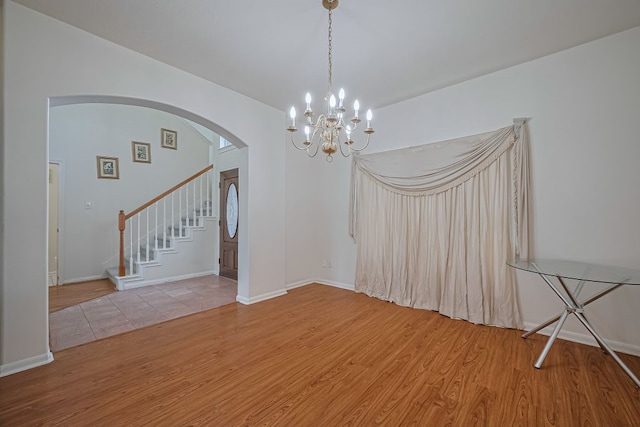 14723 Belterraza Dr, Houston, TX 77083 - spare room featuring wood finished floors, stairway, arched walkways, a chandelier, and baseboards