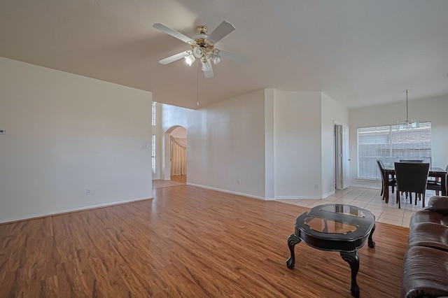 14723 Belterraza Dr, Houston, TX 77083 - living room with a ceiling fan, arched walkways, light wood-style floors, a chandelier, and baseboards