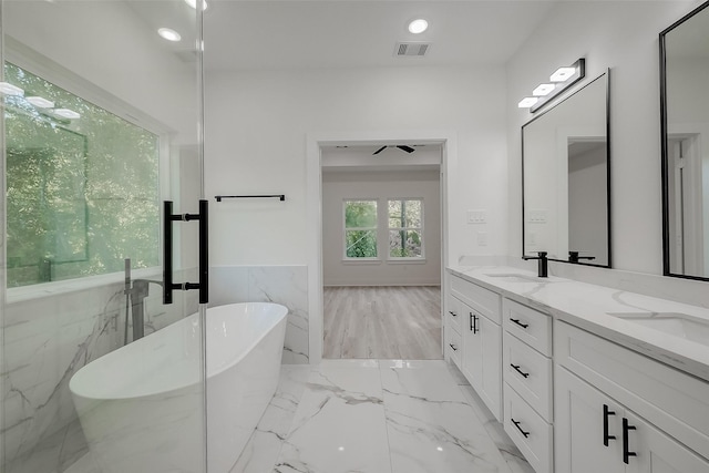 7002 Sidney St, Houston, TX 77021 - bathroom with double vanity, a freestanding tub, marble finish floors, a wainscoted wall, and tile walls