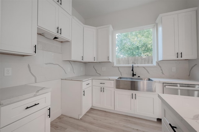 7002 Sidney St, Houston, TX 77021 - kitchen with light stone countertops, a sink, light wood finished floors, and decorative backsplash