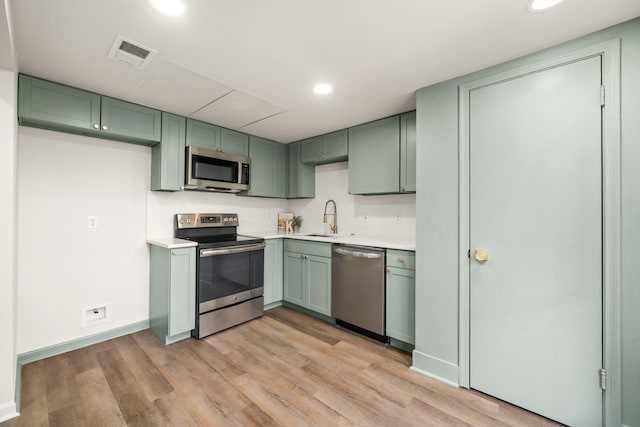 14703 Barryknoll Ln Unit 26, Houston, TX 77079 - kitchen featuring appliances with stainless steel finishes, green cabinetry, light wood-style flooring, light countertops, and recessed lighting