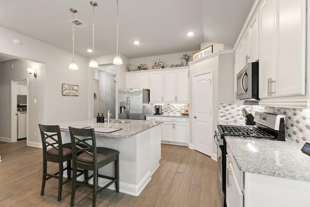 18226 Sofia Willow Way, Cypress, TX 77429 - kitchen featuring appliances with stainless steel finishes, backsplash, white cabinetry, an island with sink, and light wood-style flooring