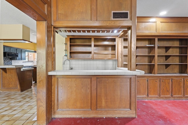 7527 Cart Gate Dr, Houston, TX 77095 - kitchen with stainless steel microwave, decorative backsplash, open shelves, and brown cabinetry
