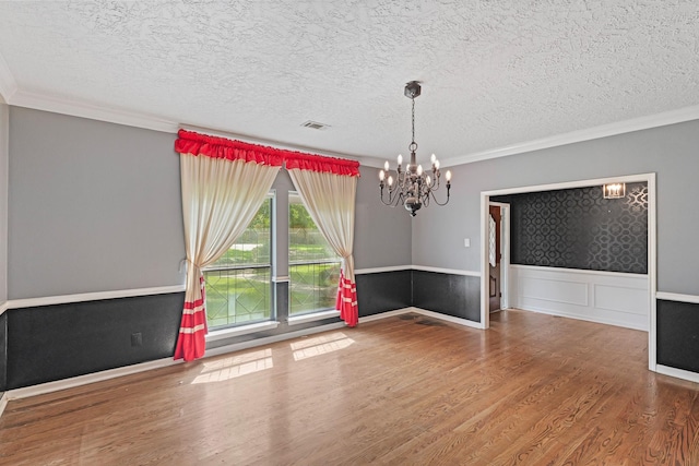 7527 Cart Gate Dr, Houston, TX 77095 - unfurnished room featuring wood finished floors, a chandelier, ornamental molding, a textured ceiling, and a wainscoted wall