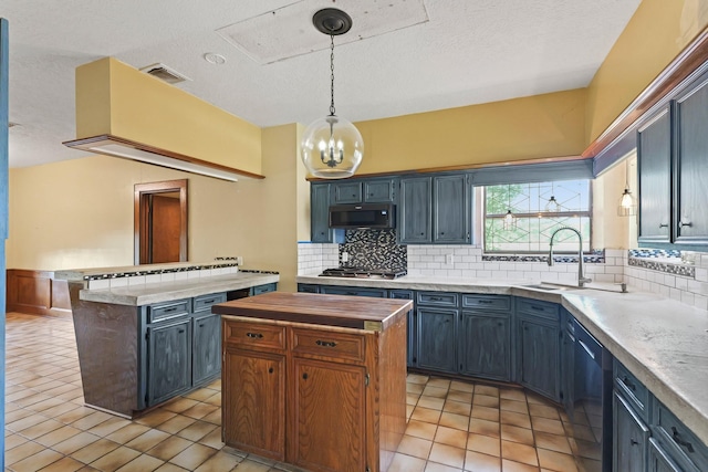 7527 Cart Gate Dr, Houston, TX 77095 - kitchen featuring appliances with stainless steel finishes, a center island, backsplash, light tile patterned flooring, and a textured ceiling