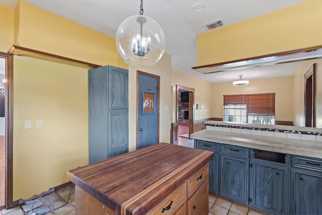 7527 Cart Gate Dr, Houston, TX 77095 - kitchen with butcher block counters, light tile patterned floors, blue cabinetry, decorative light fixtures, and a kitchen island