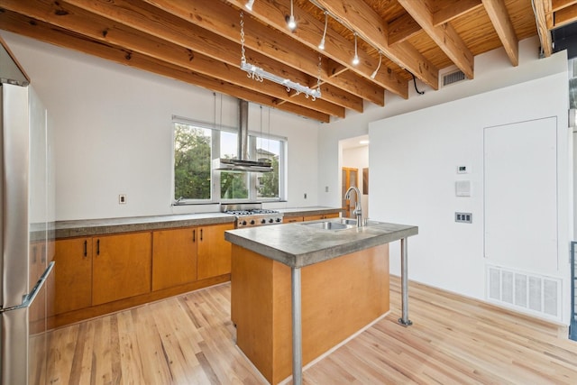 2327 Peckham St, Houston, TX 77019 - kitchen featuring freestanding refrigerator, light wood finished floors, brown cabinetry, a kitchen island with sink, and a wooden ceiling with exposed beams