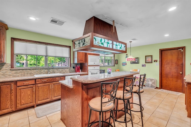 410 Azalea Dr, Baytown, TX 77520 - kitchen featuring a kitchen bar, tasteful backsplash, light tile patterned floors, white appliances, and a center island