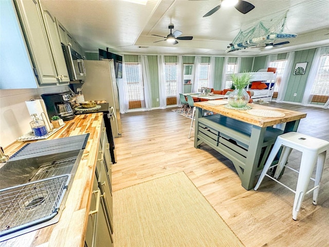 1032 N Selwyn Rd, Crystal Beach, TX 77650 - kitchen featuring butcher block counters, stainless steel microwave, light wood finished floors, and ceiling fan