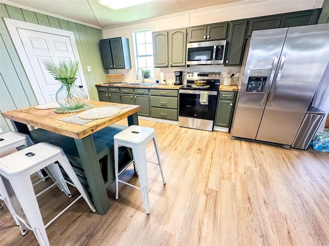 1032 N Selwyn Rd, Crystal Beach, TX 77650 - kitchen with appliances with stainless steel finishes, light wood finished floors, ornamental molding, a sink, and light countertops