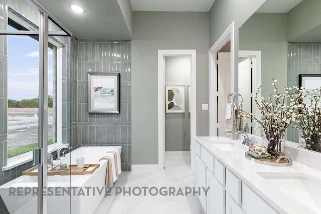 27019 Golden Isle Ln, Katy, TX 77493 - bathroom featuring a freestanding bath, double vanity, healthy amount of natural light, and marble finish flooring