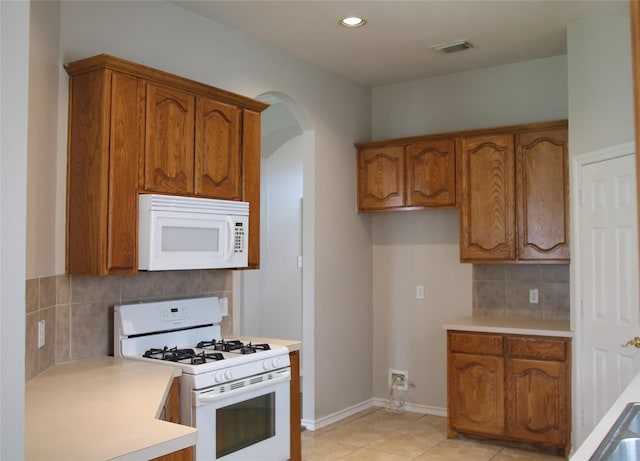 22922 Still Pond Dr, Tomball, TX 77375 - kitchen with white appliances, brown cabinets, arched walkways, light countertops, and recessed lighting
