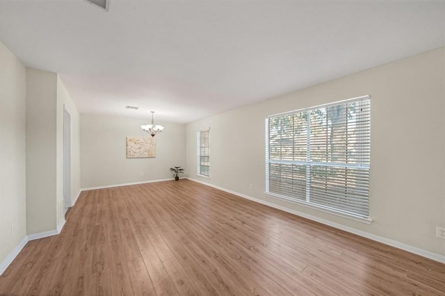 9039 Sandstone St, Houston, TX 77036 - empty room featuring a chandelier, light wood-style flooring, and baseboards