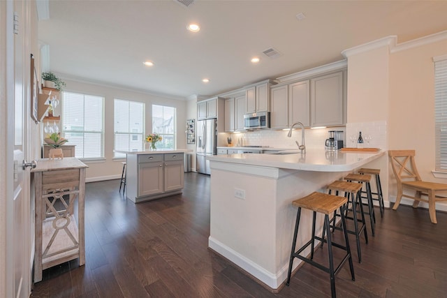 10712 Addicks Oaks Pl, Houston, TX 77043 - kitchen with stainless steel appliances, ornamental molding, a breakfast bar area, a sink, and gray cabinets