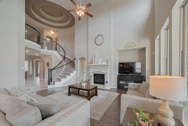 25203 Azel Shore Ct, Porter, TX 77365 - living room featuring a towering ceiling, stairs, a ceiling fan, wood finished floors, and a glass covered fireplace