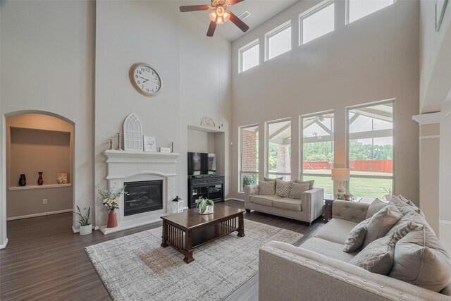 25203 Azel Shore Ct, Porter, TX 77365 - living room featuring a ceiling fan, a towering ceiling, a glass covered fireplace, and wood finished floors