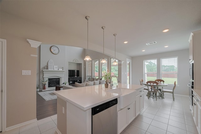 25203 Azel Shore Ct, Porter, TX 77365 - kitchen with dishwasher, light tile patterned flooring, a center island, light countertops, and a glass covered fireplace