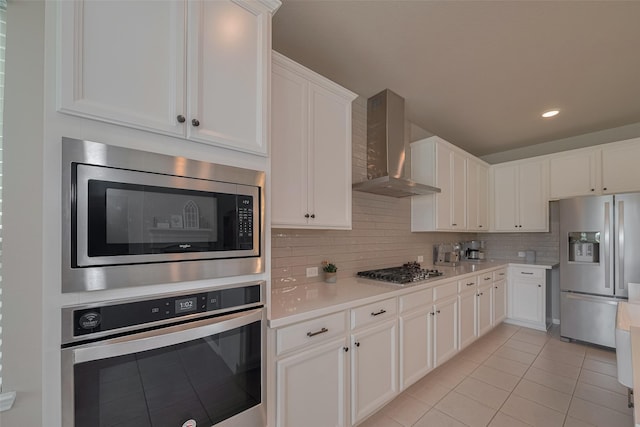 25203 Azel Shore Ct, Porter, TX 77365 - kitchen featuring wall chimney range hood, appliances with stainless steel finishes, light tile patterned flooring, light countertops, and white cabinets