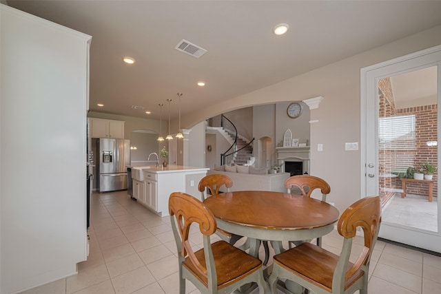 25203 Azel Shore Ct, Porter, TX 77365 - dining space featuring arched walkways, light tile patterned floors, a fireplace, and recessed lighting