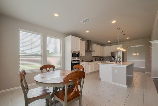 25203 Azel Shore Ct, Porter, TX 77365 - kitchen featuring wall chimney exhaust hood, appliances with stainless steel finishes, light countertops, an island with sink, and tasteful backsplash