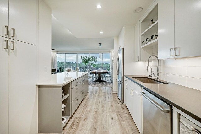 2200 Willowick Rd Unit 4E, Houston, TX 77027 - kitchen with stainless steel appliances, open shelves, a sink, light wood-style floors, and backsplash