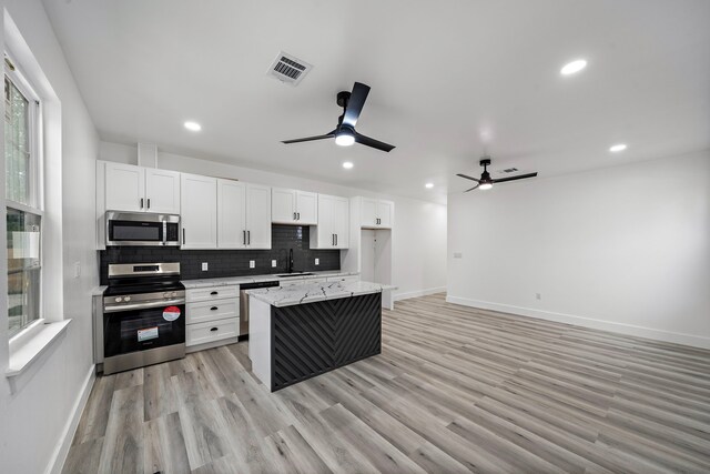 8209 Richland St A/B, Unit A/B Houston, TX 77028 - kitchen with stainless steel appliances, ceiling fan, baseboards, white cabinetry, and backsplash