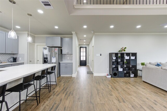 14514 Sanour Dr, Houston, TX 77084 - kitchen with stainless steel fridge with ice dispenser, ornamental molding, open floor plan, light countertops, and backsplash