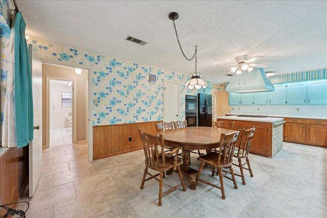 5210 Linda Ln, Beaumont, TX 77708 - dining space featuring wainscoting, a ceiling fan, a textured ceiling, wallpapered walls, and wood walls