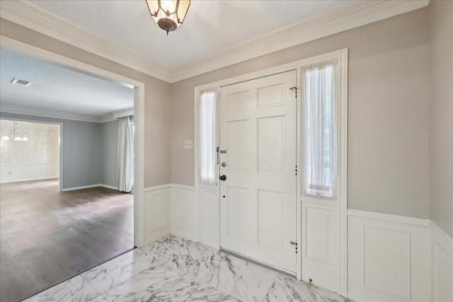 5210 Linda Ln, Beaumont, TX 77708 - foyer with a decorative wall, a wainscoted wall, light marble finish floors, crown molding, and a chandelier