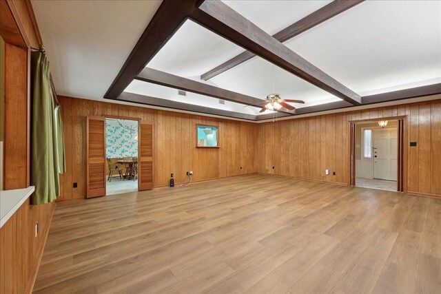 5210 Linda Ln, Beaumont, TX 77708 - unfurnished living room with wooden walls, beam ceiling, a ceiling fan, and light wood-type flooring