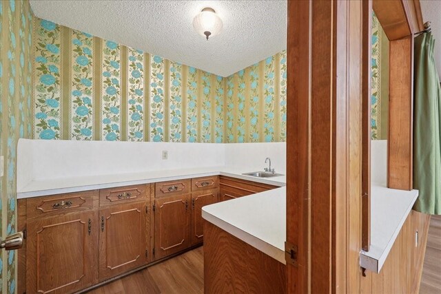 5210 Linda Ln, Beaumont, TX 77708 - bathroom with wallpapered walls, a sink, wood finished floors, and a textured ceiling