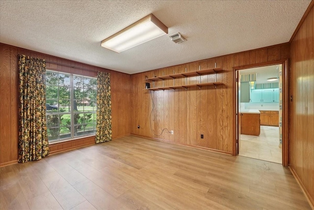 5210 Linda Ln, Beaumont, TX 77708 - spare room featuring light wood finished floors, wooden walls, and a textured ceiling