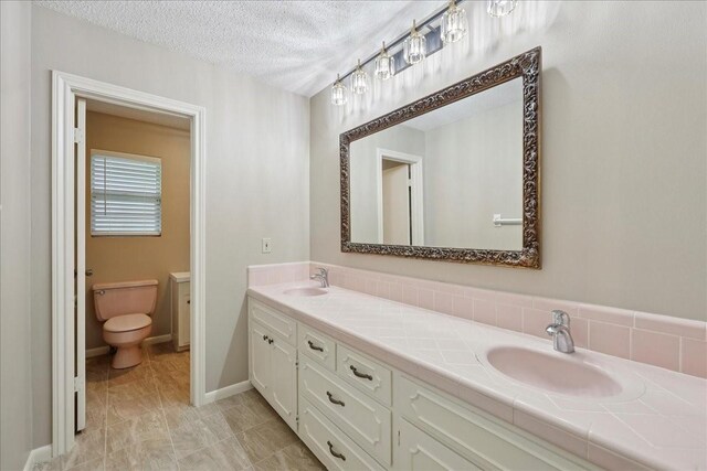 5210 Linda Ln, Beaumont, TX 77708 - full bath with toilet, double vanity, and a textured ceiling