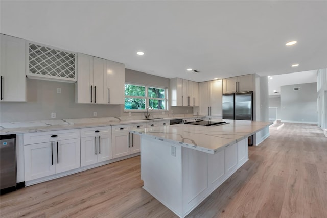 2702 Fairway Dr, Sugar Land, TX 77478 - kitchen with a sink, a center island, light wood-style flooring, light stone counters, and white cabinetry