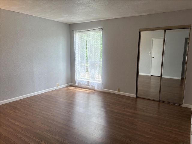17230 Imperial Valley Dr Unit 24, Houston, TX 77060 - unfurnished bedroom featuring dark wood-type flooring, a textured wall, baseboards, a textured ceiling, and a closet