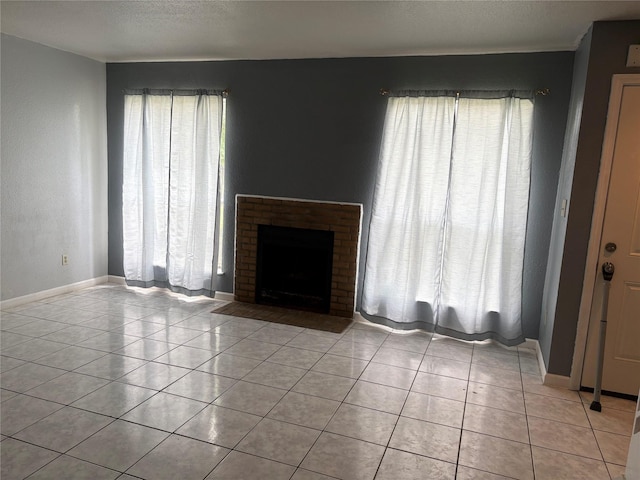 17230 Imperial Valley Dr Unit 24, Houston, TX 77060 - unfurnished living room with light tile patterned floors, a brick fireplace, baseboards, and a textured ceiling