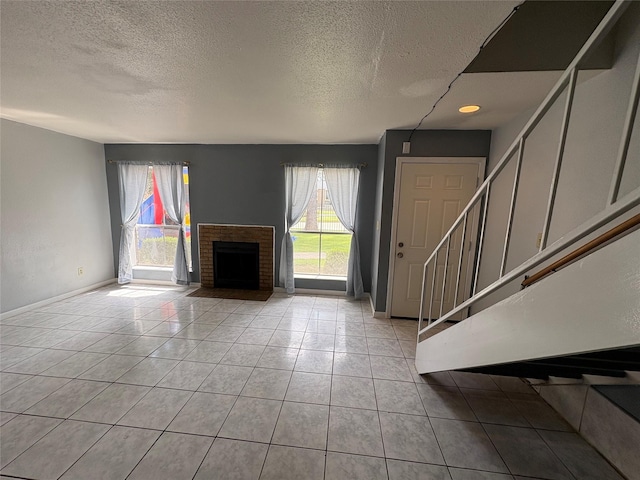 17230 Imperial Valley Dr Unit 24, Houston, TX 77060 - unfurnished living room featuring stairway, a textured ceiling, light tile patterned flooring, and a fireplace