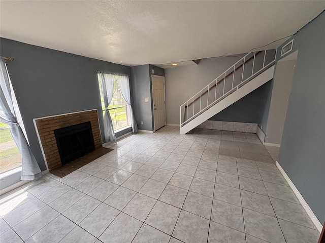 17230 Imperial Valley Dr Unit 24, Houston, TX 77060 - unfurnished living room featuring light tile patterned floors, a textured ceiling, a fireplace, and stairway