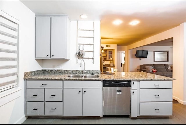 10305 Bassoon Dr, Houston, TX 77025 - kitchen with stainless steel dishwasher, a sink, a peninsula, light stone counters, and baseboards