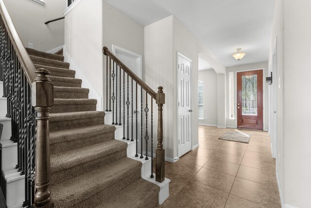 6411 St Placidia Dr, Spring, TX 77379 - foyer entrance featuring stairway, arched walkways, baseboards, and tile patterned floors