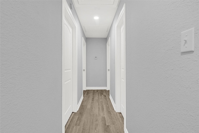 11423 Raincove Dr, Houston, TX 77016 - hallway featuring wood finished floors, baseboards, a textured wall, and attic access