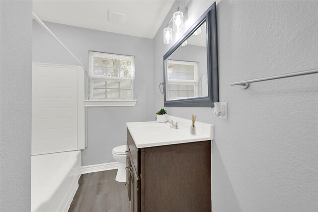 11423 Raincove Dr, Houston, TX 77016 - full bathroom featuring vanity, toilet, wood finished floors, baseboards, and a textured wall