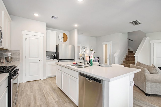 40557 Mostyn Lake Dr, Magnolia, TX 77354 - kitchen featuring stainless steel appliances, a sink, open floor plan, backsplash, and white cabinetry