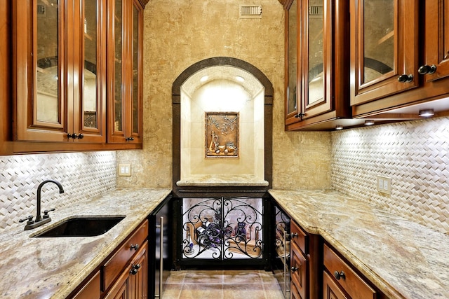 4503 Summits Edge Ln, Katy, TX 77494 - kitchen featuring light stone countertops, tasteful backsplash, glass insert cabinets, and brown cabinetry