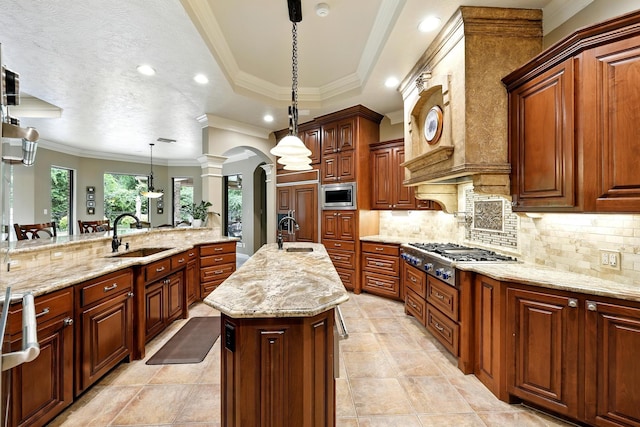 4503 Summits Edge Ln, Katy, TX 77494 - kitchen featuring appliances with stainless steel finishes, a center island with sink, arched walkways, ornate columns, and light stone counters